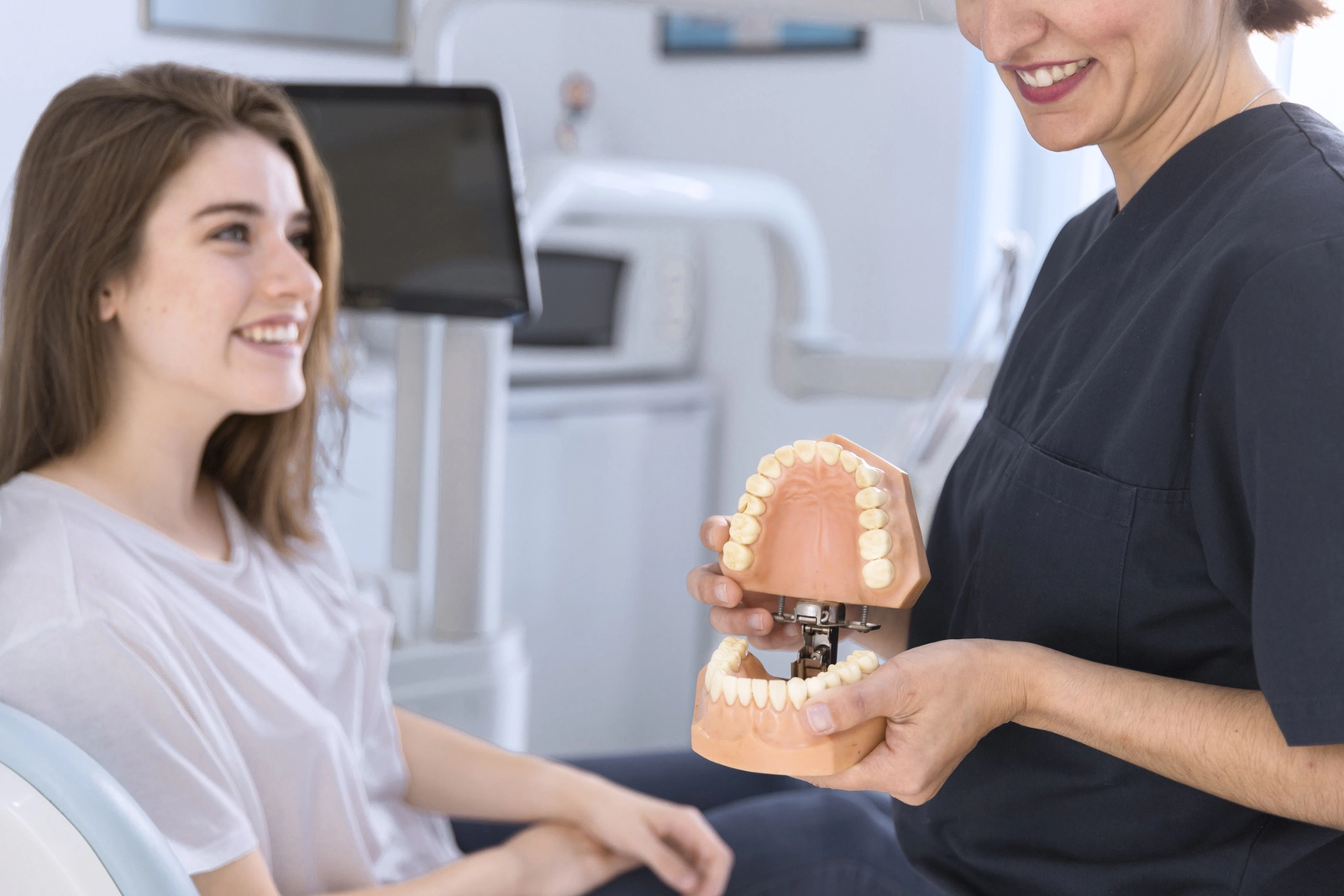 How To Choose An Orthodontist: A patient listening to a dental professional holding a model of the teeth