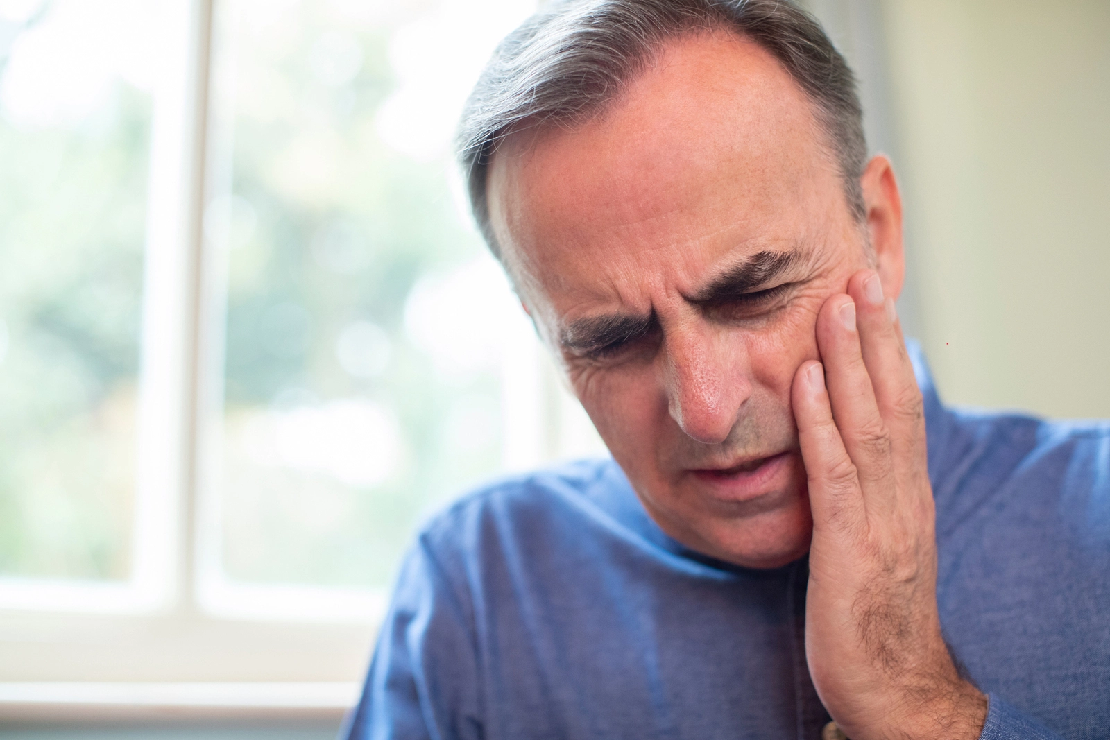 How To Fix a Chipped Tooth: A man holding the side of his jaw as if in pain.