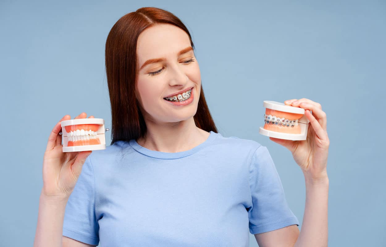Is An Overbite Bad? A person with braces holding two teeth models