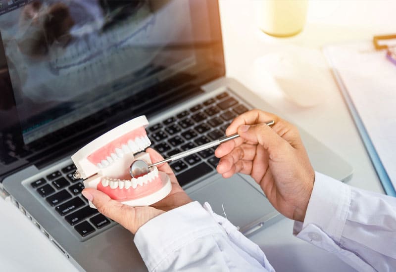 A dental professional examining dental x-rays and a dental model
