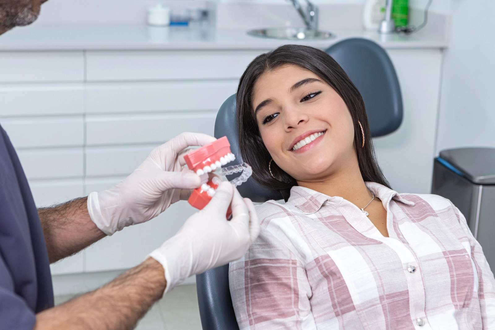 Orthodontic Appliances: A woman in a dentist chair being shown clear aligners by an orthodontist.